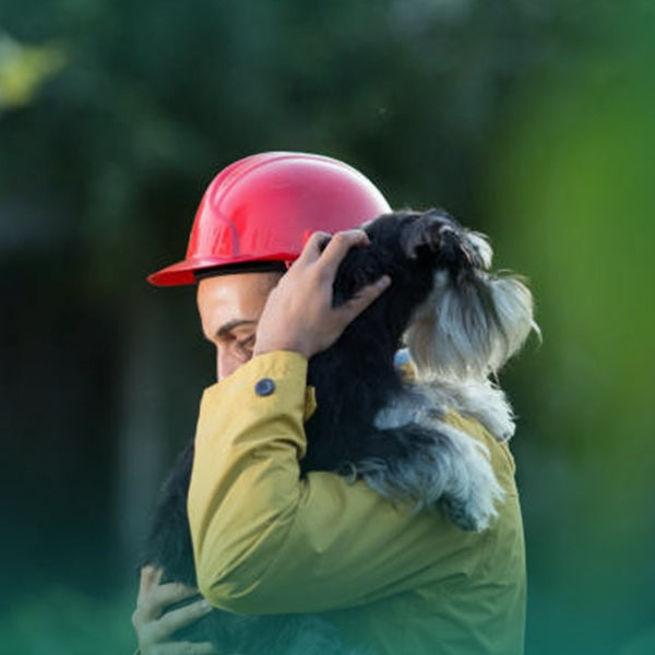 Rescue worker hugging a dog after finding it, representing pet recovery, safety, and tracking technology.